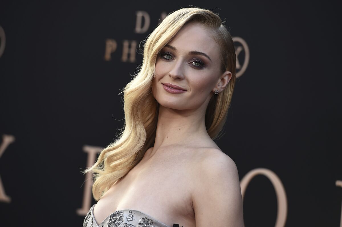A blond Sophie Turner poses in a strapless dress
