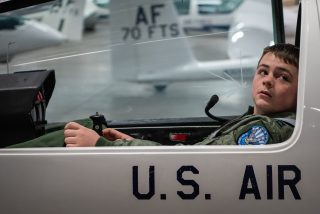 A boy in a flight suit tries out a cockpit at the U.S. Air Force Academy.