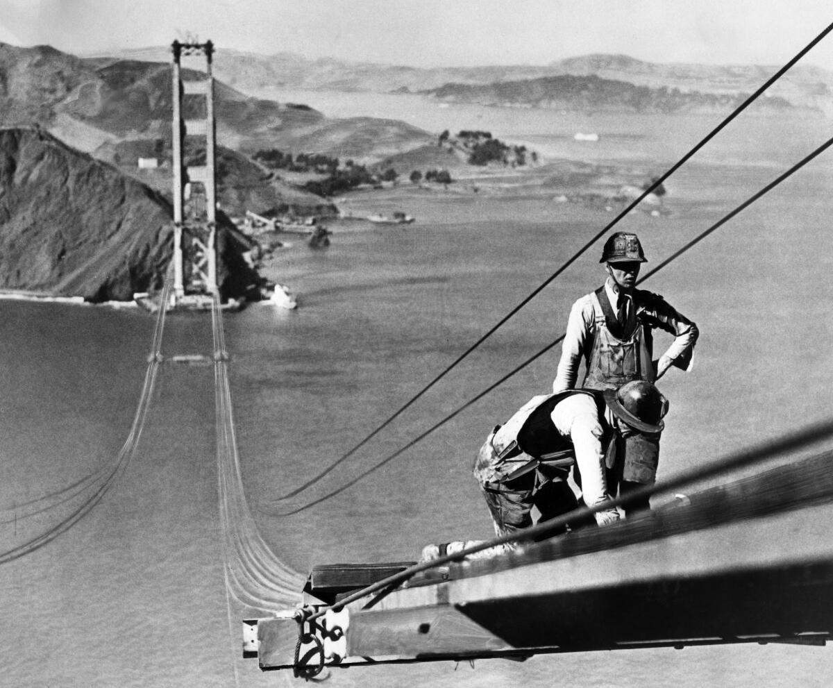 Workers atop cables of a bridge