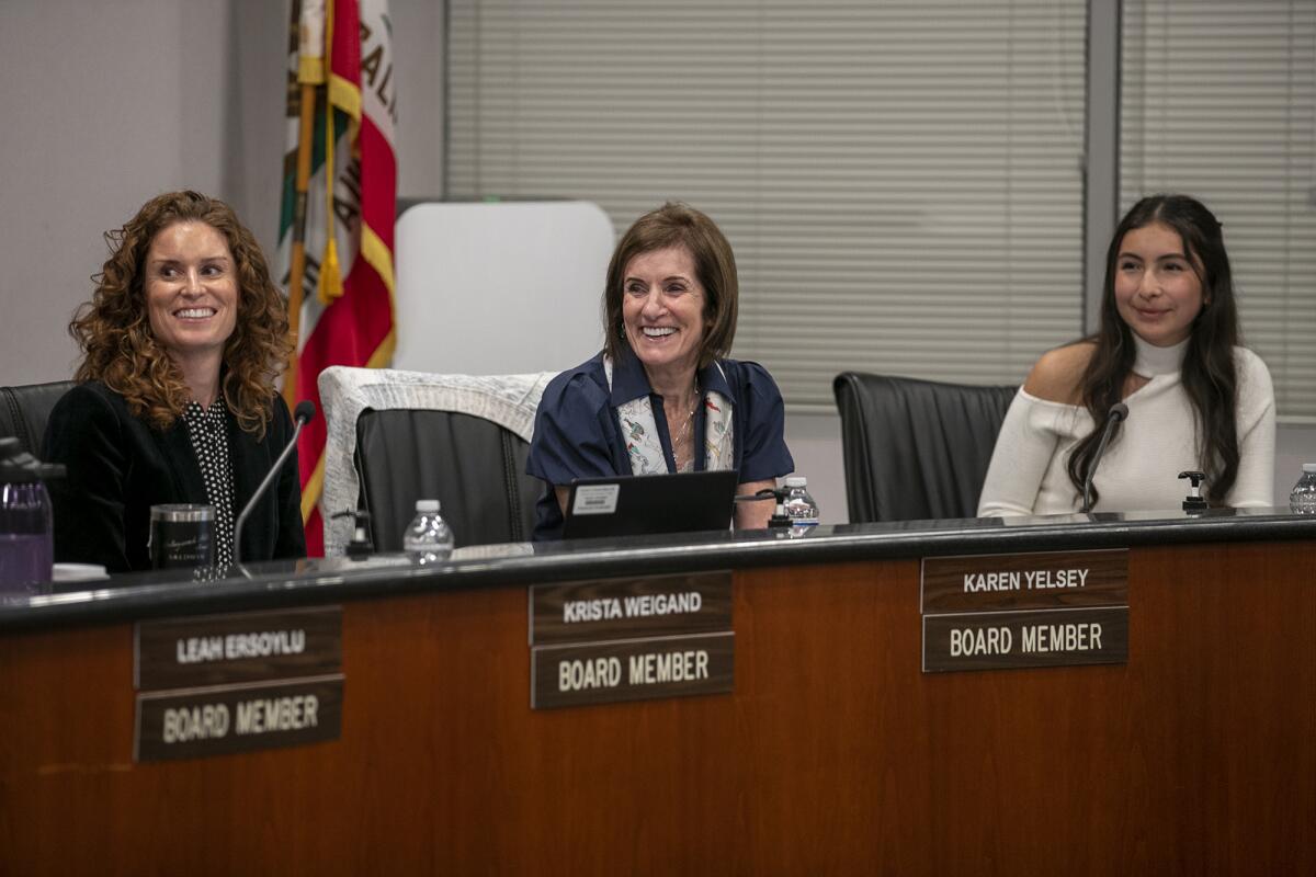  Karen Yelsey, center, smiles as Newport-Mesa Unified President Michelle Barto commends her for her 24 years on the board.