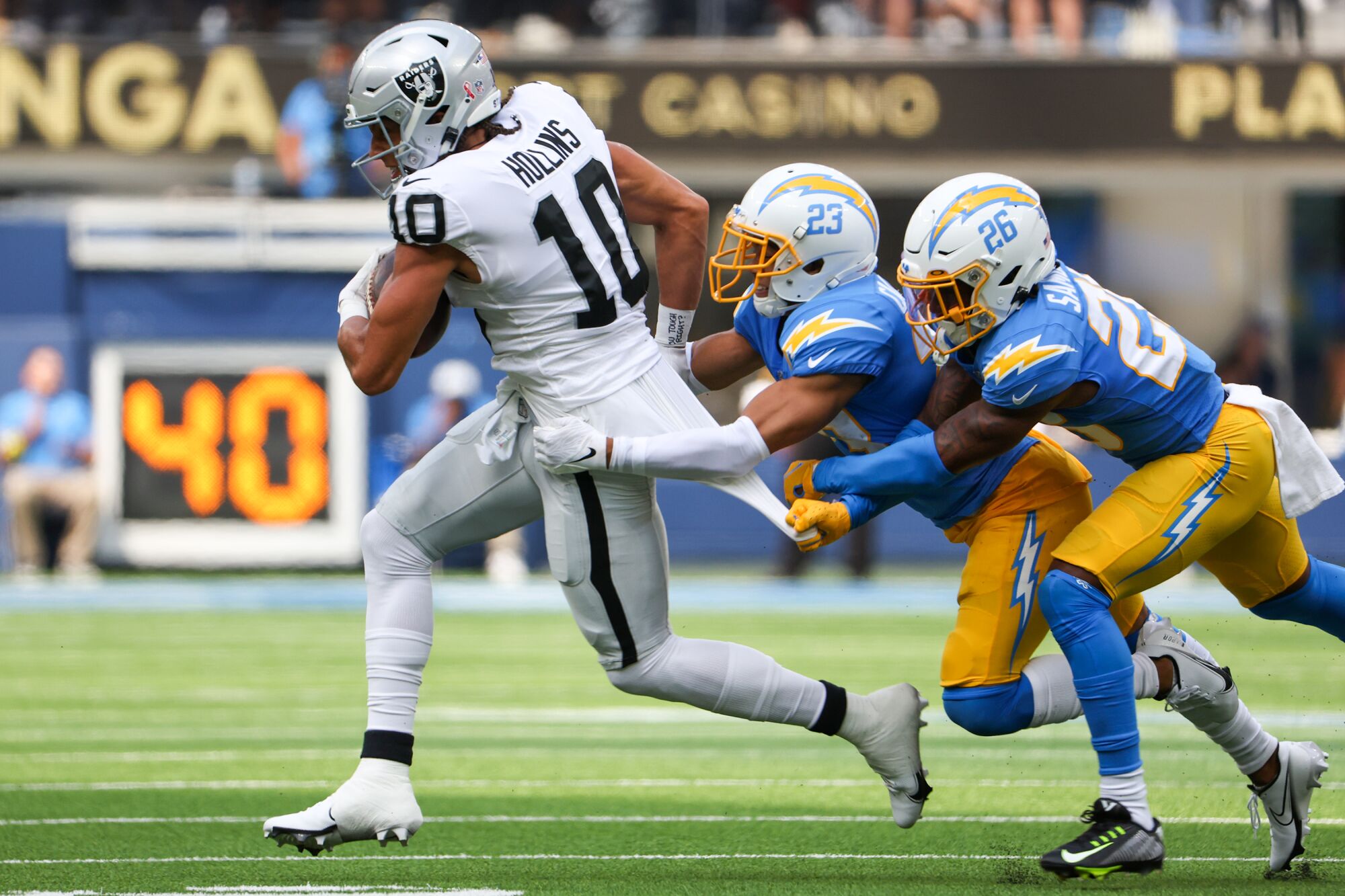 Le receveur large des Raiders Mack Hollins tente de secouer les tacles du demi de coin Bryce Callahan et Asante Samuel Jr.