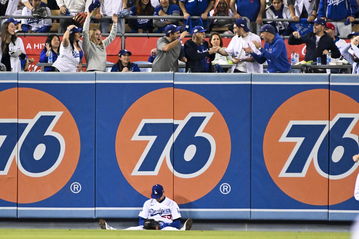 Trayce Thompson slumps against a row of 76 gasoline ads on the outfield wall at Dodger Stadium.