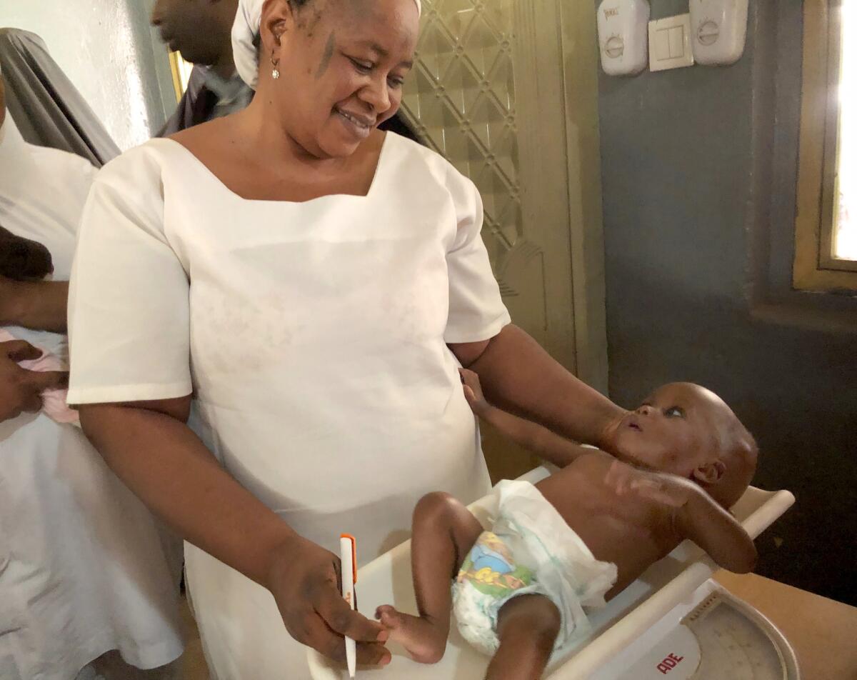 Aisha Usman, in charge of the high-calorie food supplement stock at the Badarawa Primary Health Care Center in Kaduna, Nigeria, with 8-month-old Hassan Shuaibu Yusuf, son of Amina Adamu.
