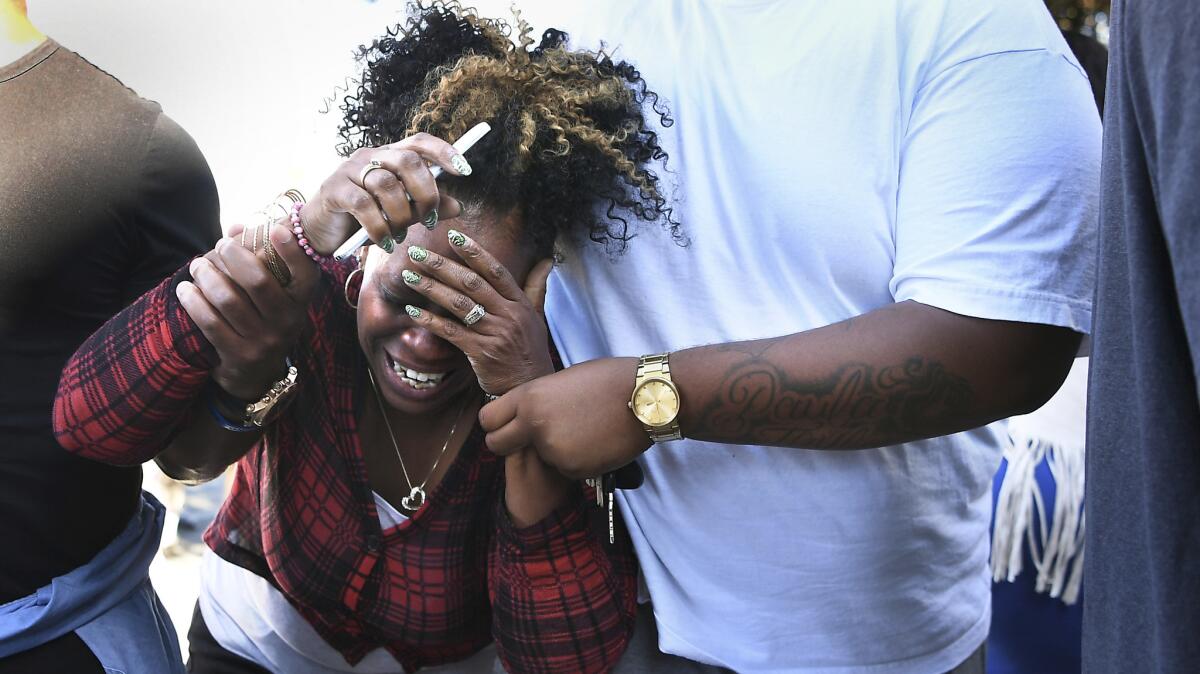 A woman breaks down as a L.A. County Coronor van leaves a residence in Pasadena.