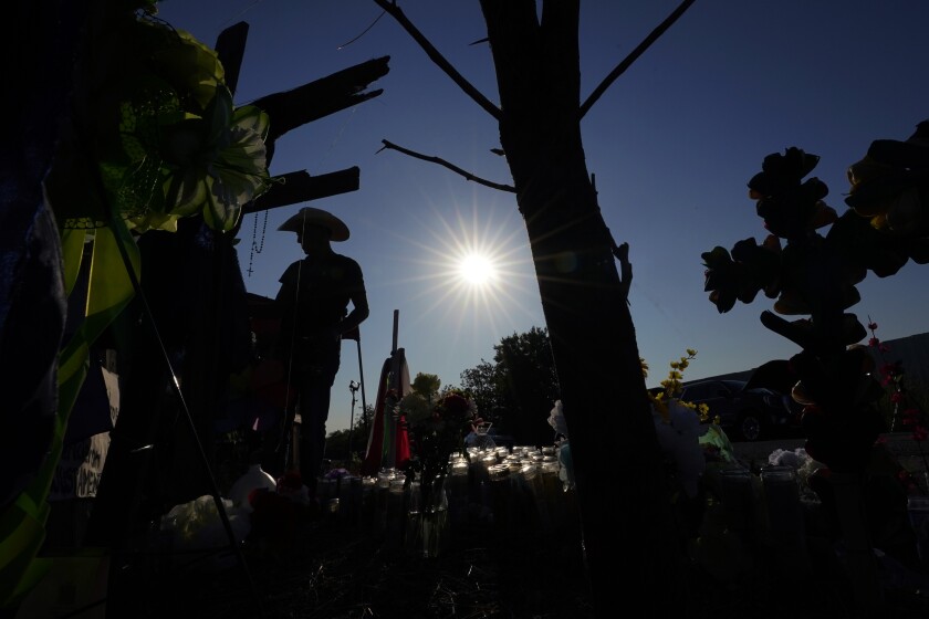 Roberto Marquez adds a cross to a makeshift memorial at the site where officials more than 50 people dead in an abandoned semitrailer containing suspected migrants, Thursday, June 30, 2022, in San Antonio. (AP Photo/Eric Gay)