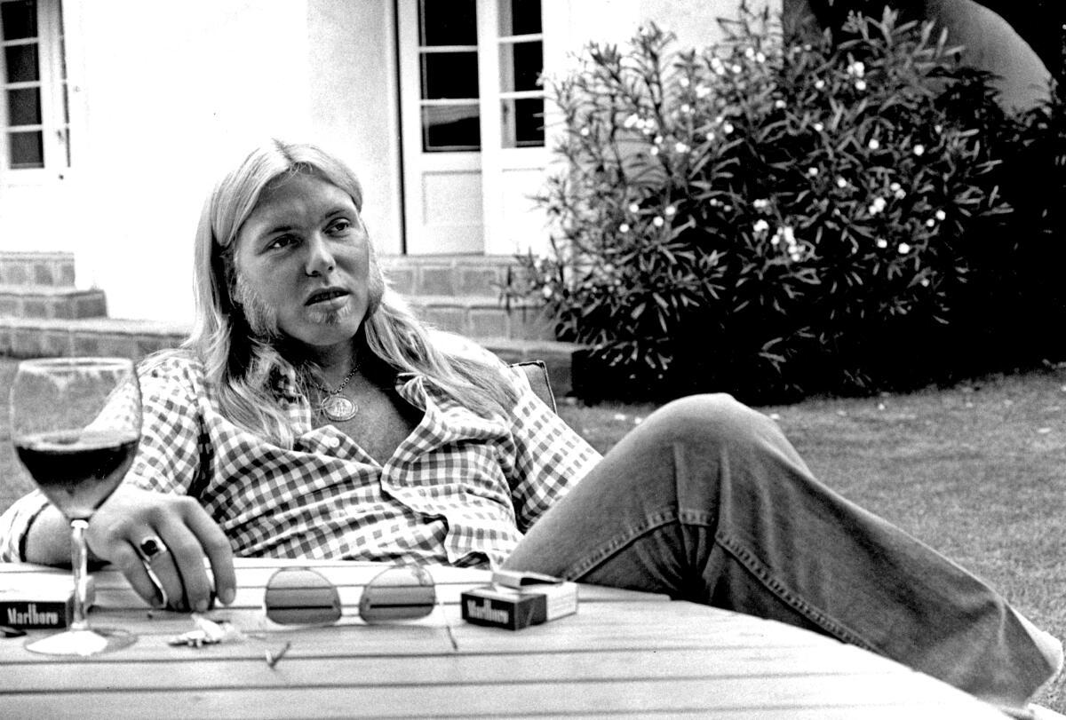 Gregg Allman sits at a table in 1976.