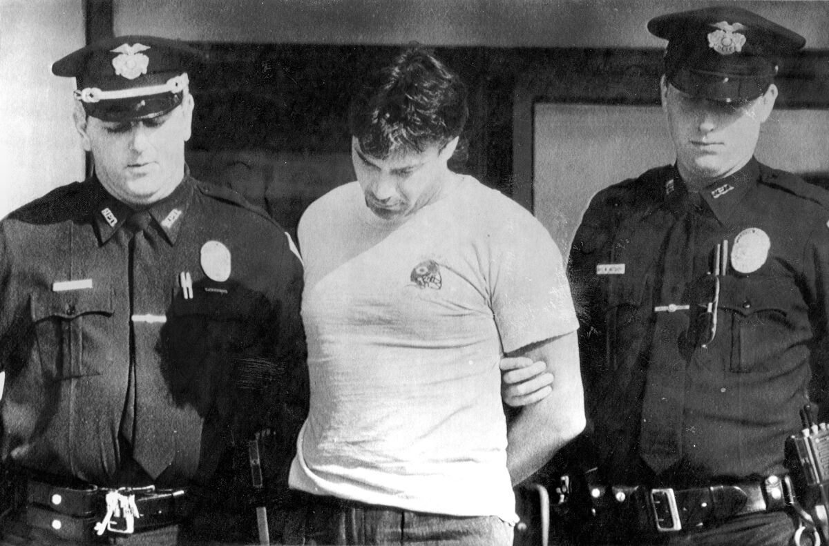 FILE - Peter Dushame, 33, of North Andover, Mass., center, is lead out of Nashua District Court in Nashua, N.H. on Oct. 3, 1989, after his arraignment on a negligent homicide charge. Dushame, who was found guilty of manslaughter, earned a master's degree in counseling psychology and changed his name to Peter Stone while in prison, and was released in 2002. In July 2021, he was arrested on charges he sexually assaulted a woman he was counseling in North Conway, N.H. (AP Photo/File)