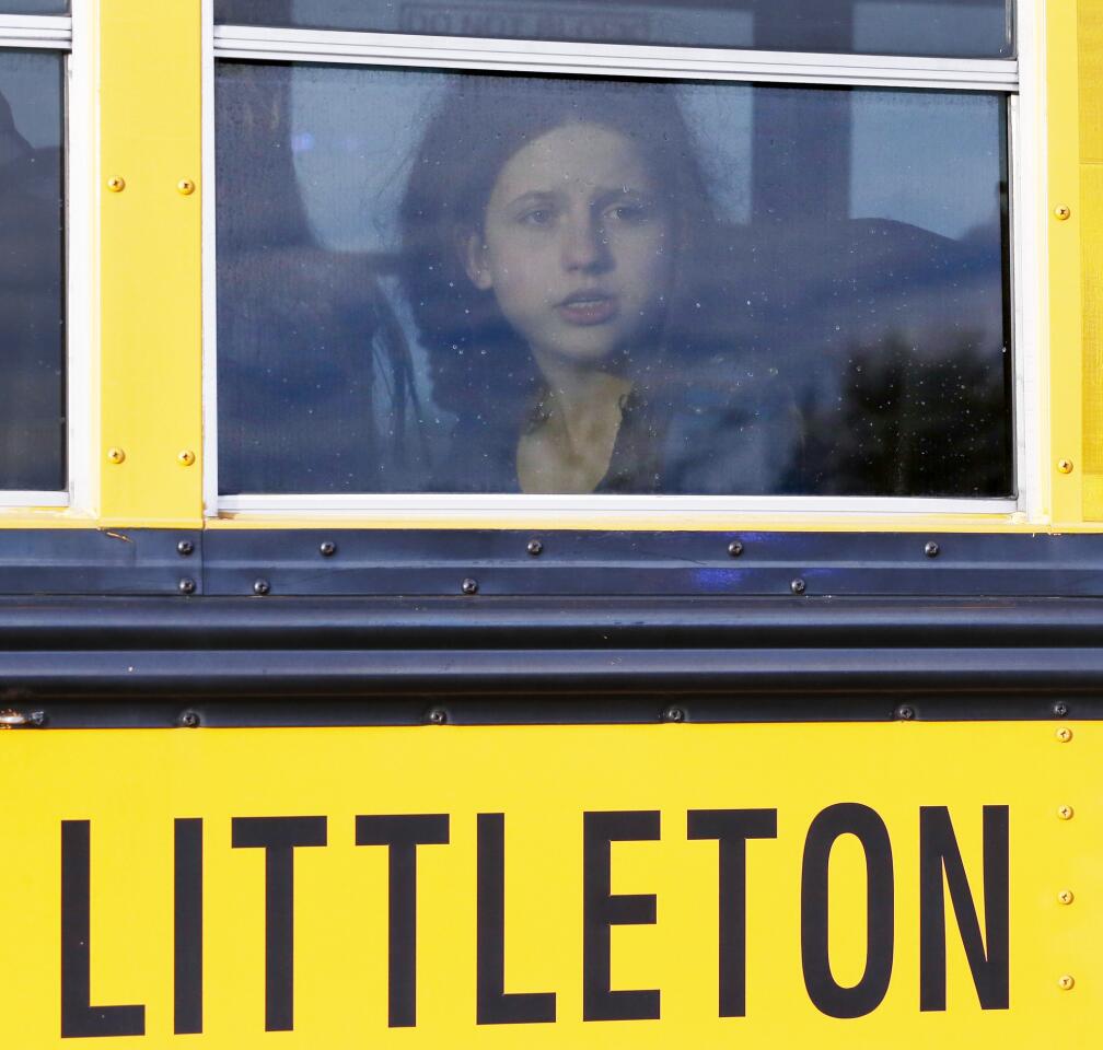 A student stares out a bus window as it arrives at a church where she was reunited with her family after Arapahoe High School was evacuated when a student with a shotgun opened fire, wounding too classmates before apparently turning the gun on himself.