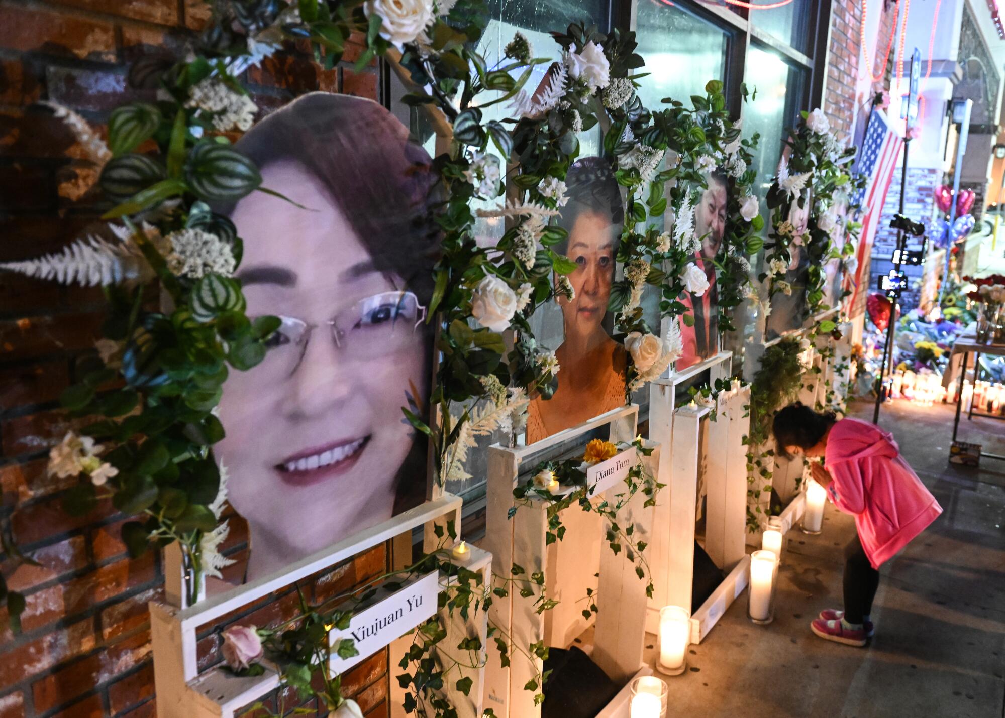 A girl bows before portraits of Monterey Park shooting victims.