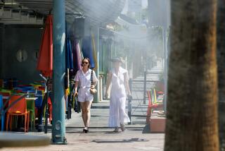 PALM SPRINGS, CA - JULY 8, 2024: Tourists walk under cooling misters as the temperature reaches 118 degrees on July 8, 2024 in Palm Springs, California.(Gina Ferazzi / Los Angeles Times)