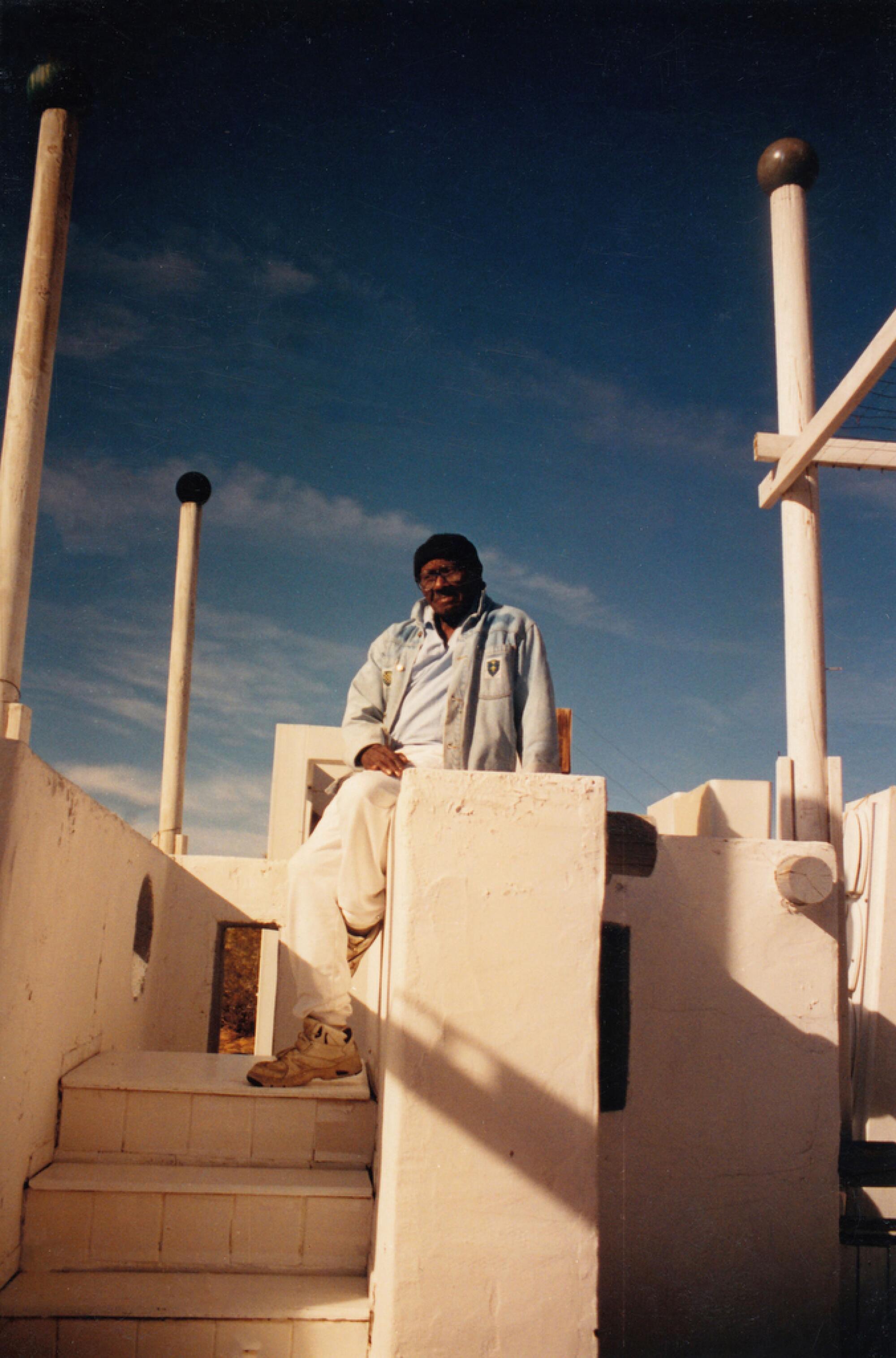 Noah Purifoy sitting in The White House, 1990-93. Courtesy of Noah Purifoy Foundation 2021