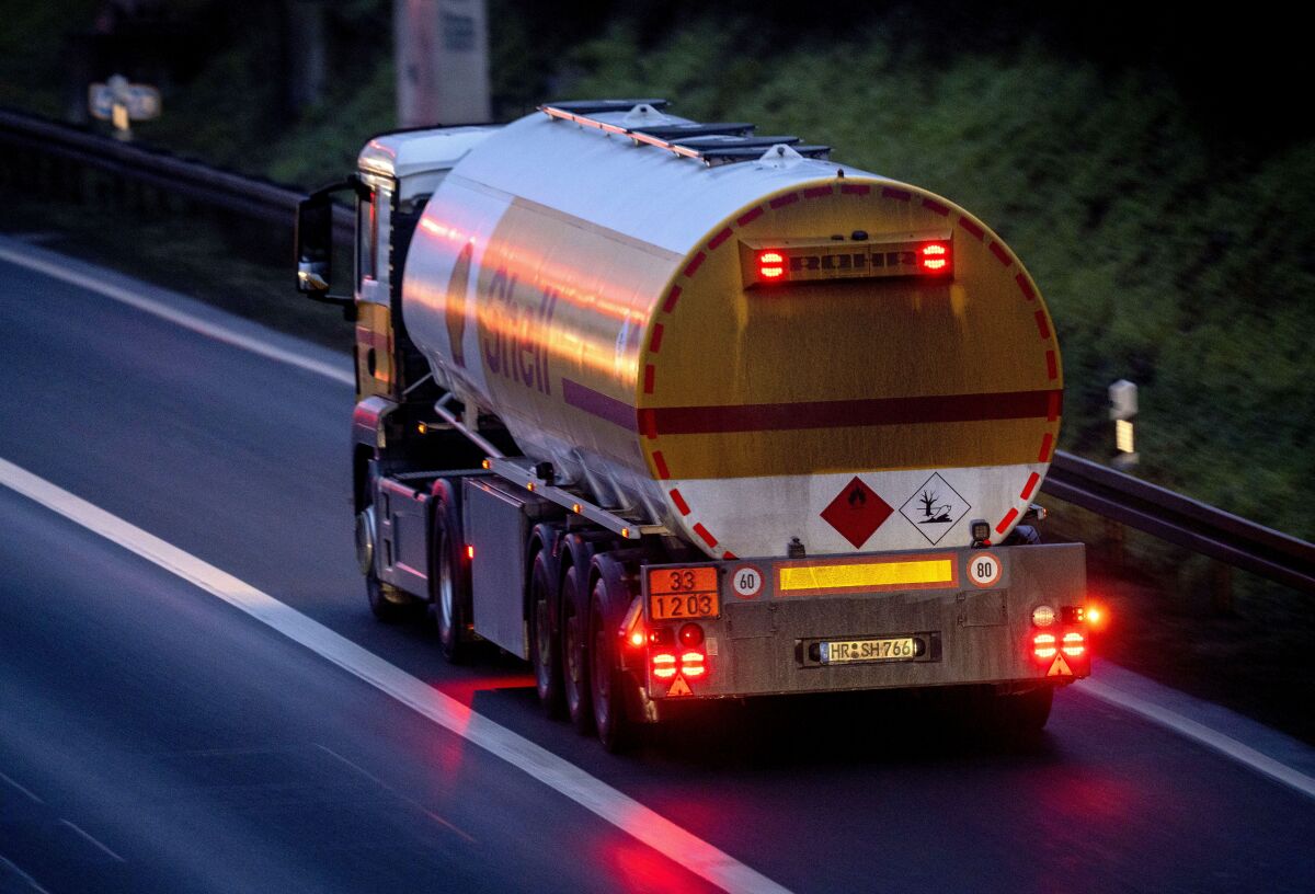 A fuel truck drives along a highway at night.
