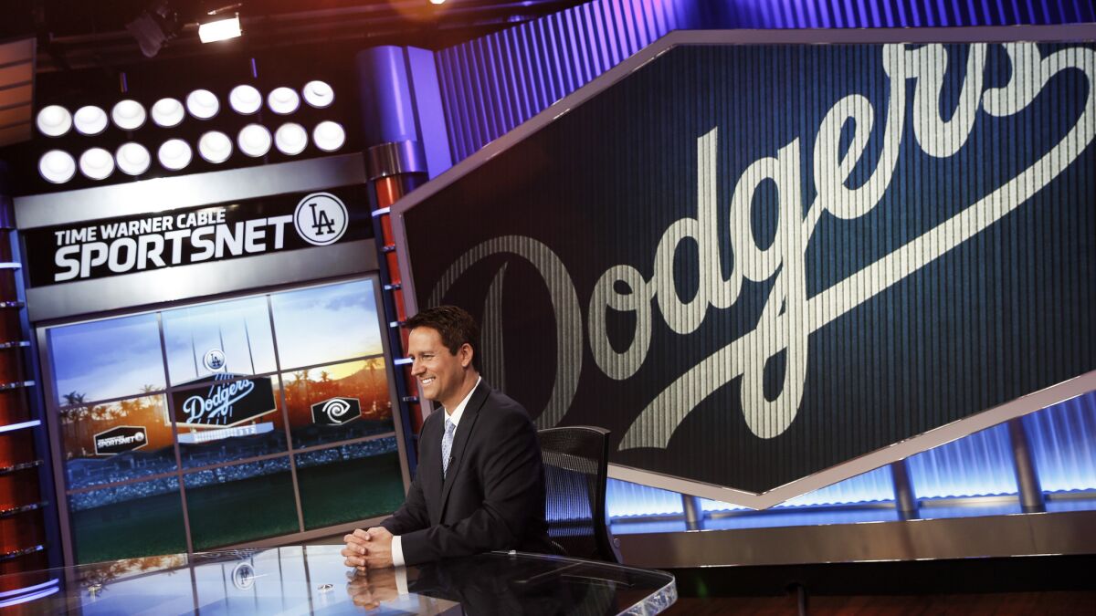 SportsNet LA anchor John Hartung sits in the television station's main studio in El Segundo. Time Warner Cable and the Dodgers are pushing for an arbitrator to determine a fair distribution price for the channel.