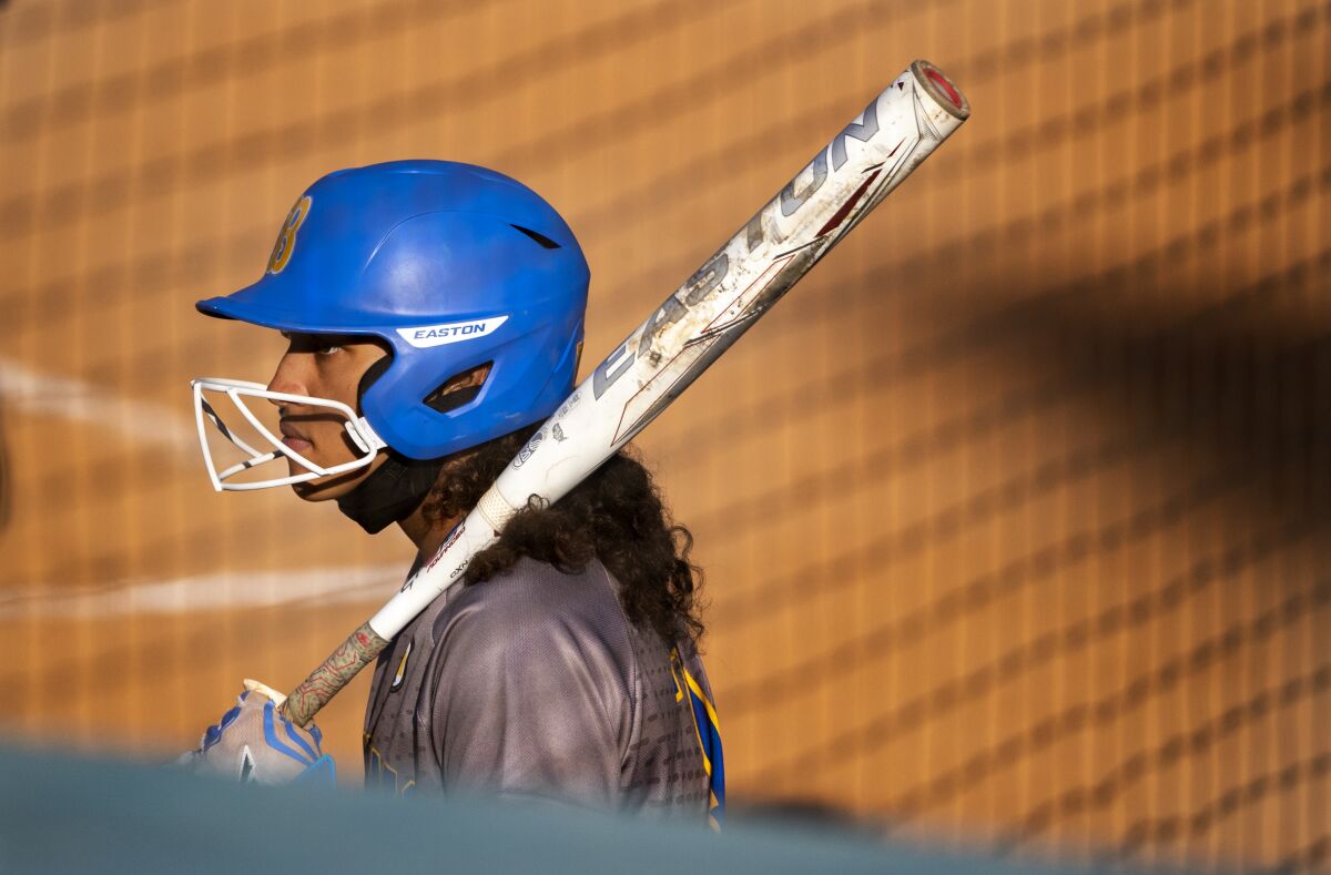 A softball player waits on deck before her turn to bat.