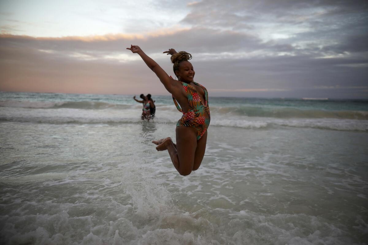 Una turista estadounidense brinca para una foto en la playa de Tulum, México.
