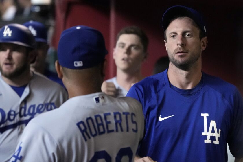 Los Angeles Dodgers' Max Scherzer talks to manager Dave Roberts (30) in the dugout before the team's baseball game against the Arizona Diamondbacks, Saturday, July 31, 2021, in Phoenix. (AP Photo/Rick Scuteri)