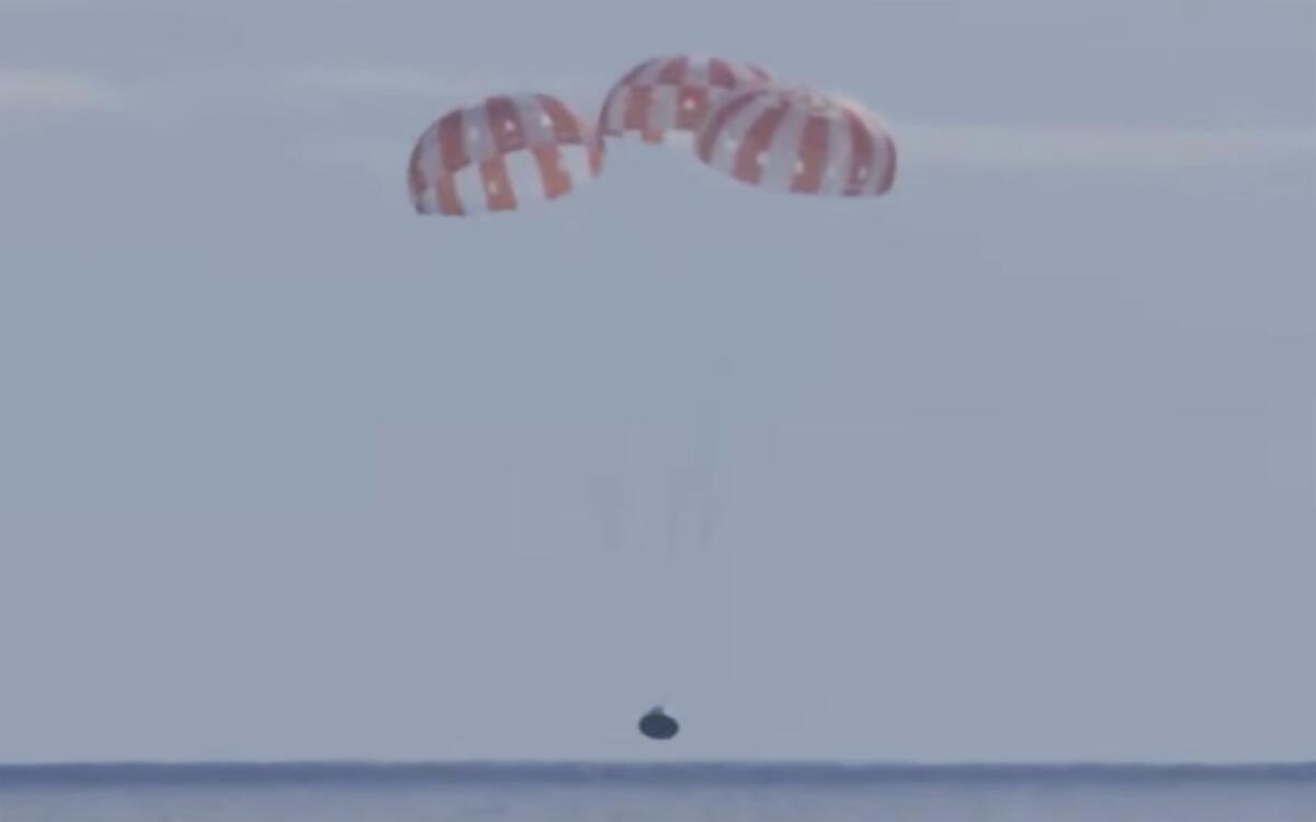 The Orion capsule is suspended from parachutes