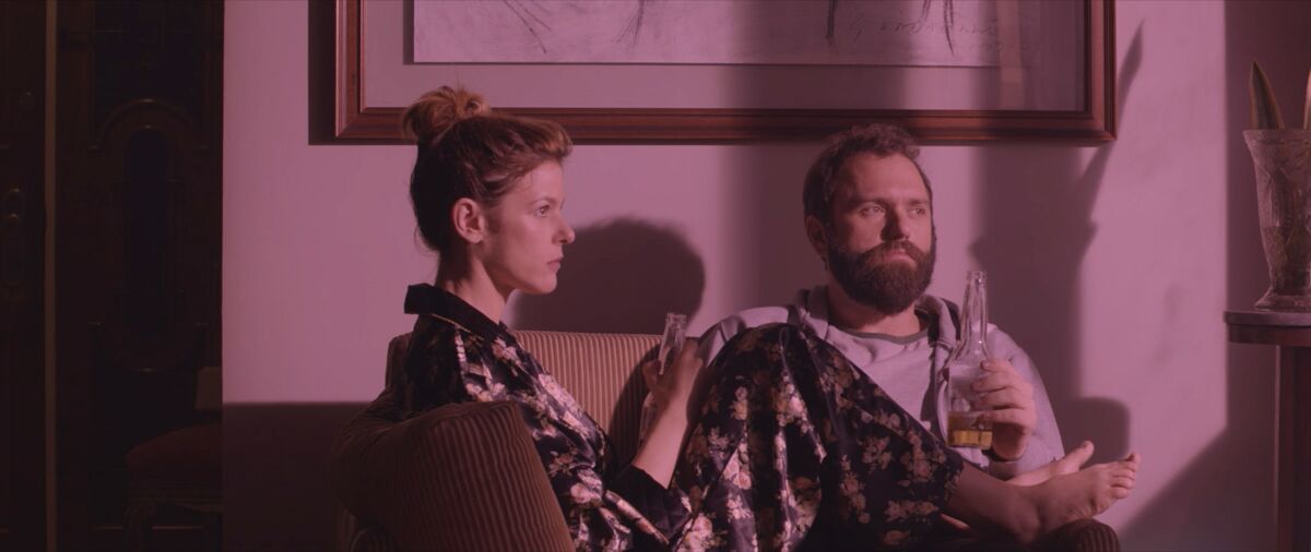 A man and a woman gaze out a window in the movie “The Pink Cloud”
