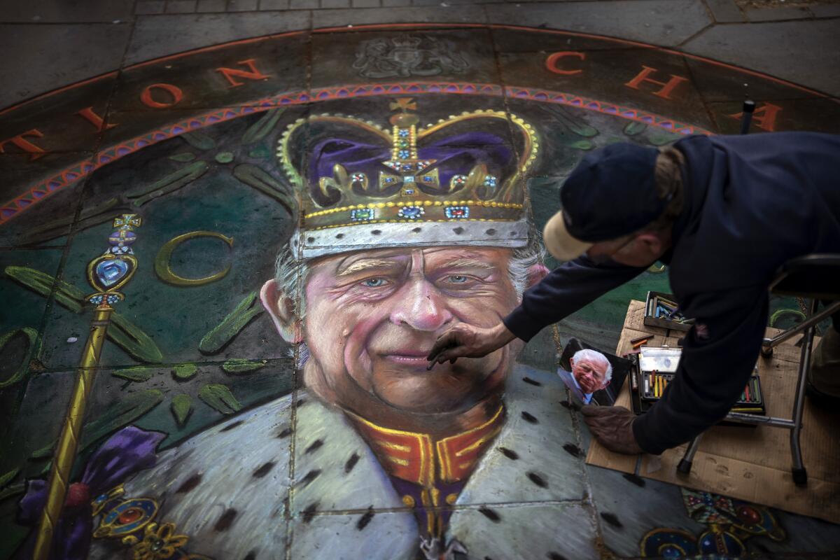 A chalk artist working on a portrait of King Charles III.