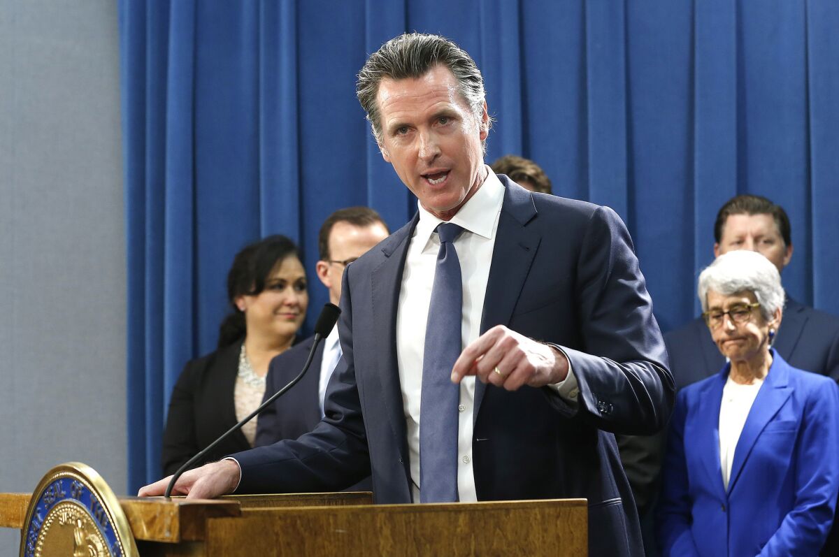 California Governor Gavin Newsom speaks at a lectern during a news conference