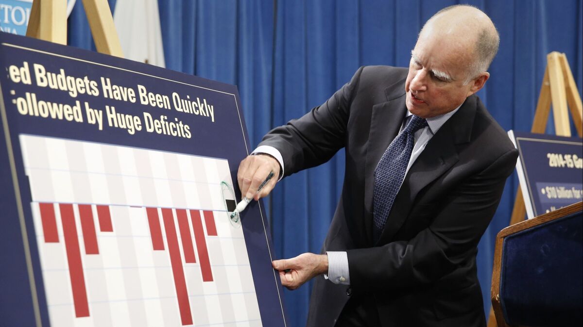Gov. Jerry Brown circles a black line showing a surplus for the coming year at a Sacramento news conference at which he unveiled his proposed 2014-15 budget.