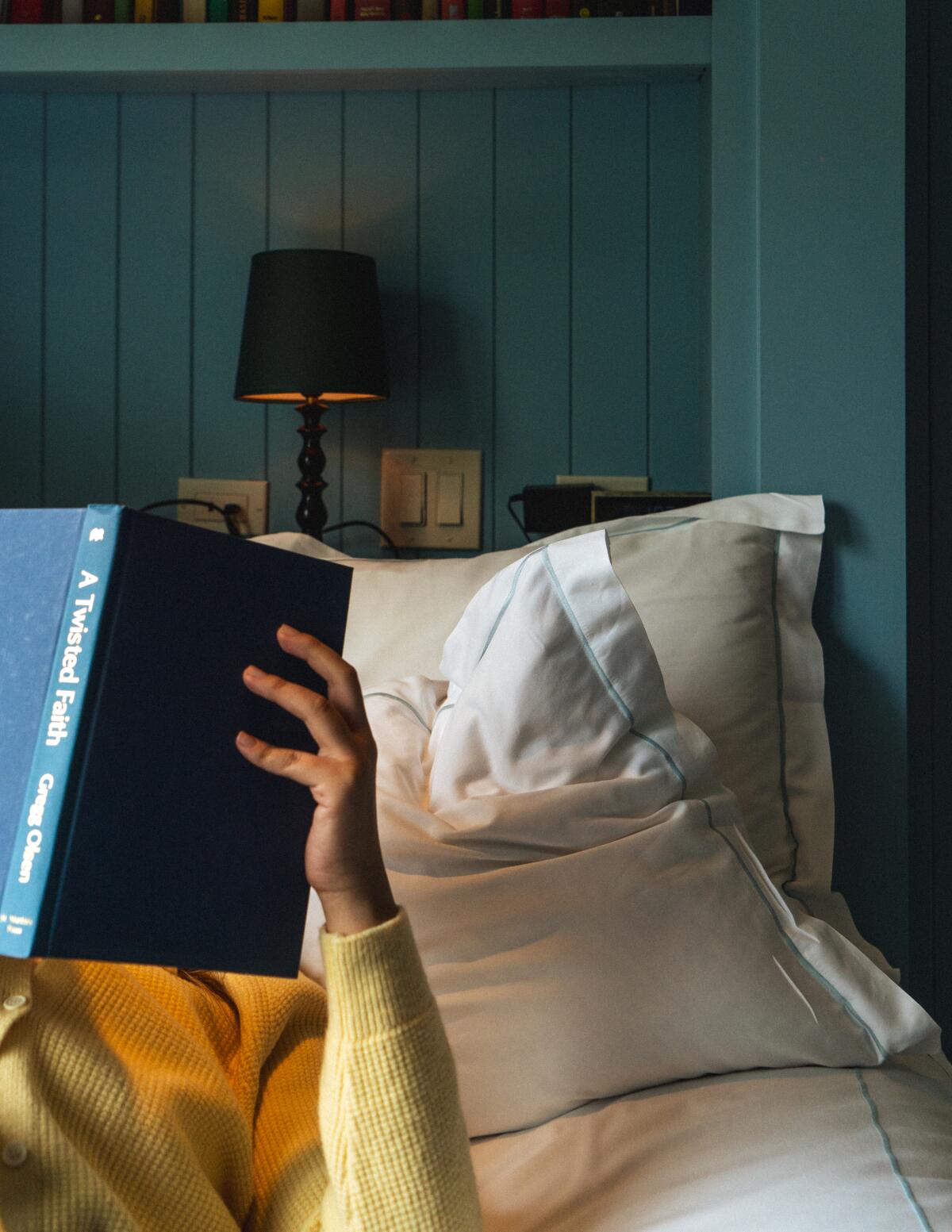 A person looks at a book in bed.