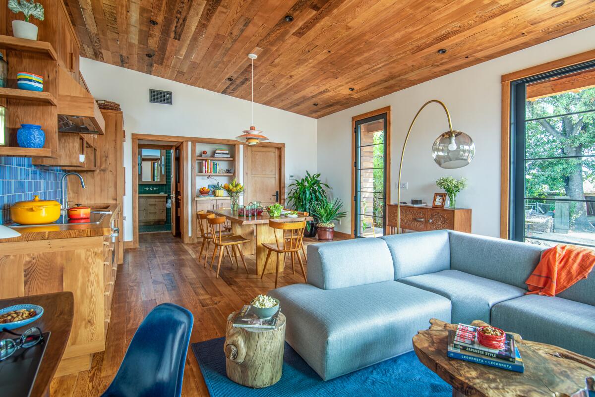 The living, dining room and kitchen of an ADU features wood floors, ceiling and cabinets. 