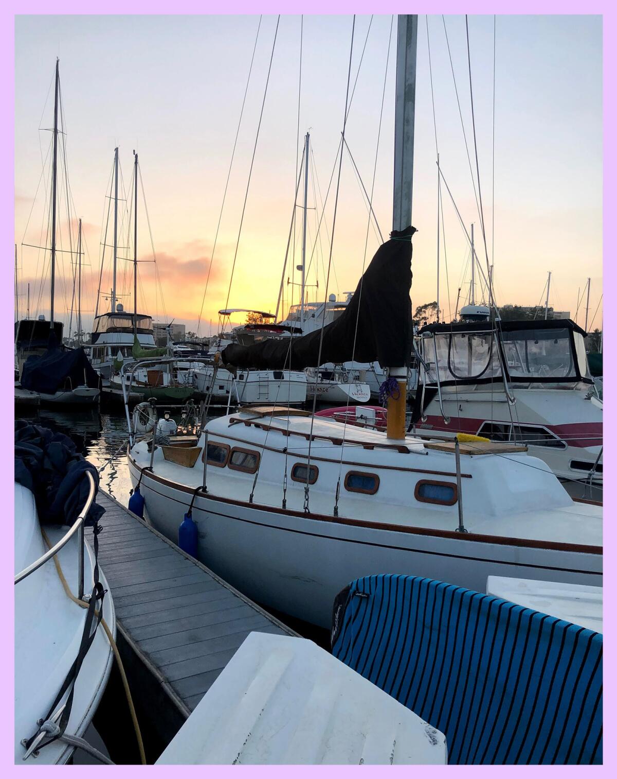 A boat docked in a marina with the setting sun in the background