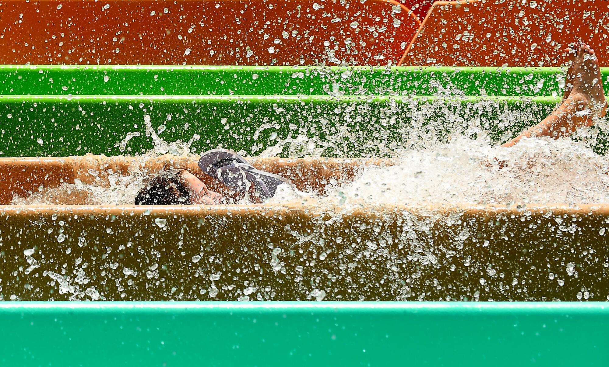A person splashes at the end of a waterslide ride