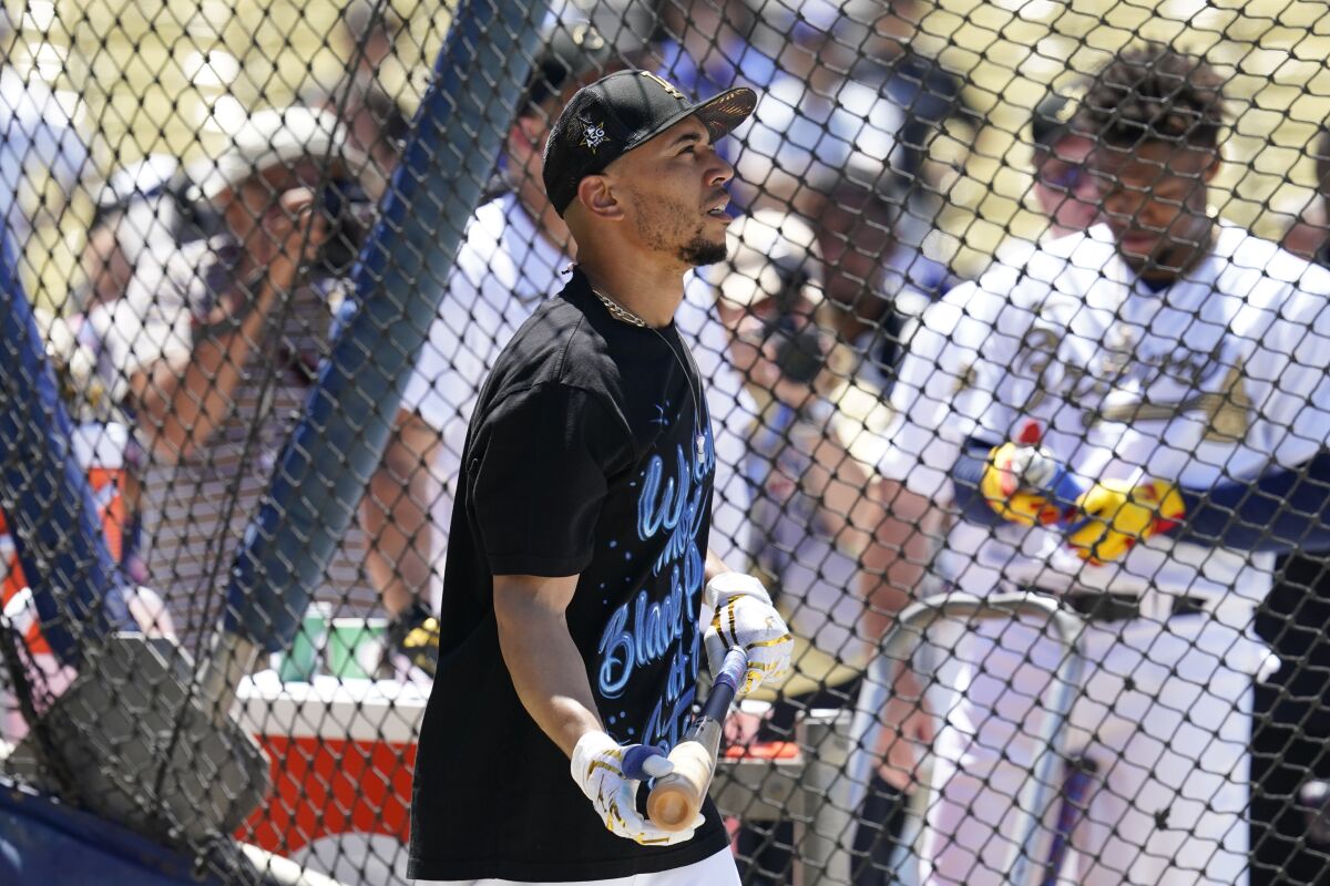 Dodgers outfielder Mookie Betts holds a bat  while wearing a black T-shirt and hat