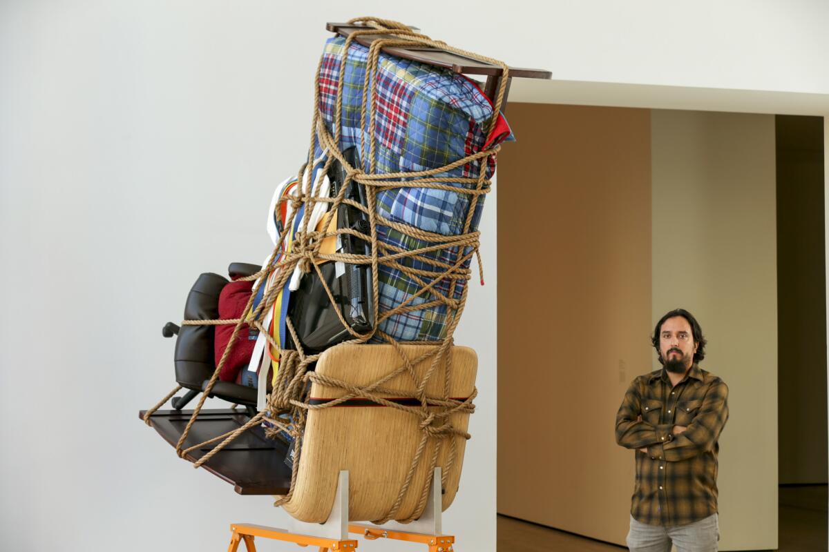 Artist Camilo Ontiveros with a sculpture he created with the belongings of a DACA recipient. (Irfan Khan / Los Angeles Times)
