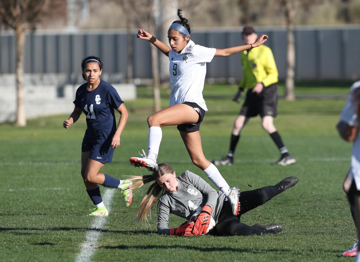 Costa Mesa's Bryanna Elias (9) leaps over Calvary Chapel goalie Taylor Foss (1) during an Orange Coast League game.