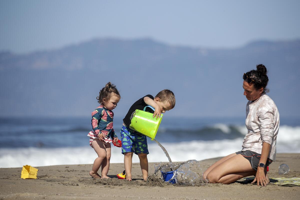 A mother and two young children build san castles on Dockweiler State Beach.   