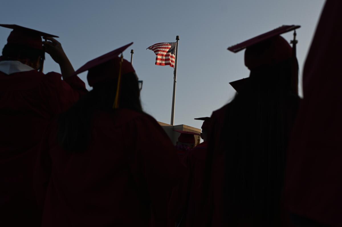 A U.S. flag and people with graduation caps and gowns.