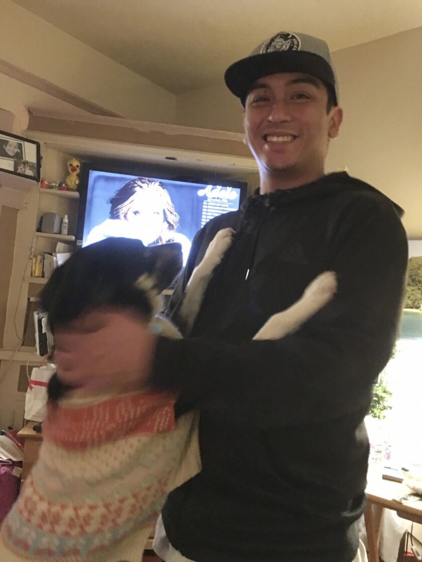 Angelo Quinto is shown smiling with a dog next to him