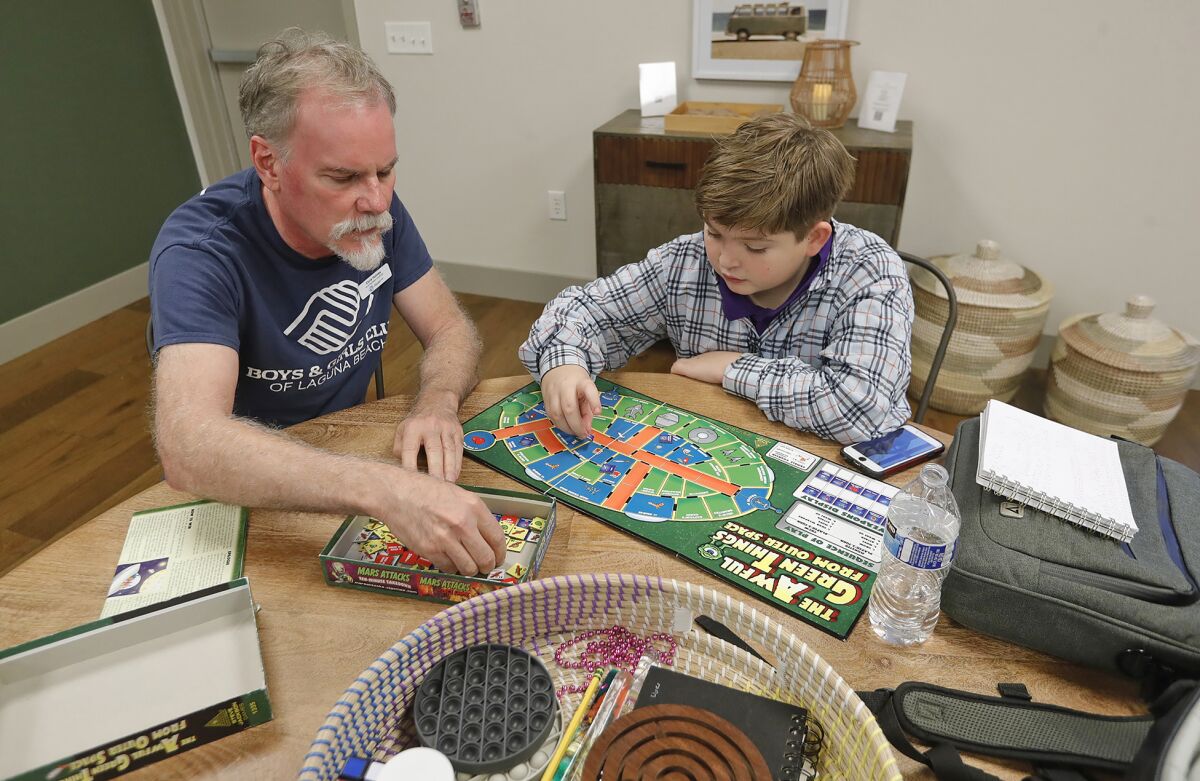 Chris Holmes of the Boys & Girls Club plays a game with a member of the club as part of the new well space room.
