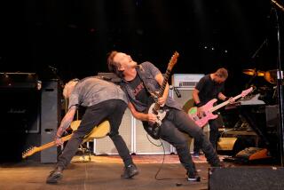 Mike McCready and Eddie Vedder and members of Pearl Jam are leaning against each other while strumming guitars on stage