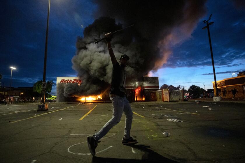 A protester near a burning AutoZone store in Minneapolis on Wednesday night.