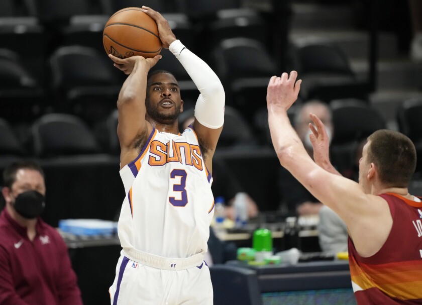Phoenix Suns guard Chris Paul, left, shoots for a basket as Denver Nuggets center Nikola Jokic defends in the first half of Game 4 of an NBA second-round playoff series Sunday, June 13, 2021, in Denver. (AP Photo/David Zalubowski)