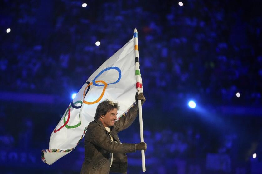 Tom Cruise carries the Olympic flag during the 2024 Summer Olympics closing ceremony at the Stade de France, Sunday, Aug. 11, 2024, in Saint-Denis, France. (AP Photo/Natacha Pisarenko)