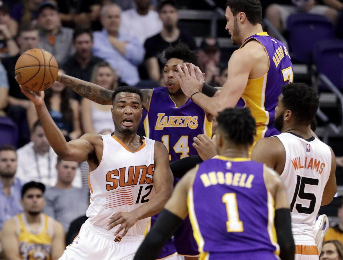 Suns forward T.J. Warren passes the ball away from Lakers forward Brandon Ingram (14) as forward Larry Nance Jr. (7) and guard D'Angelo Russell (1) defend during the first half of a game on March 9.