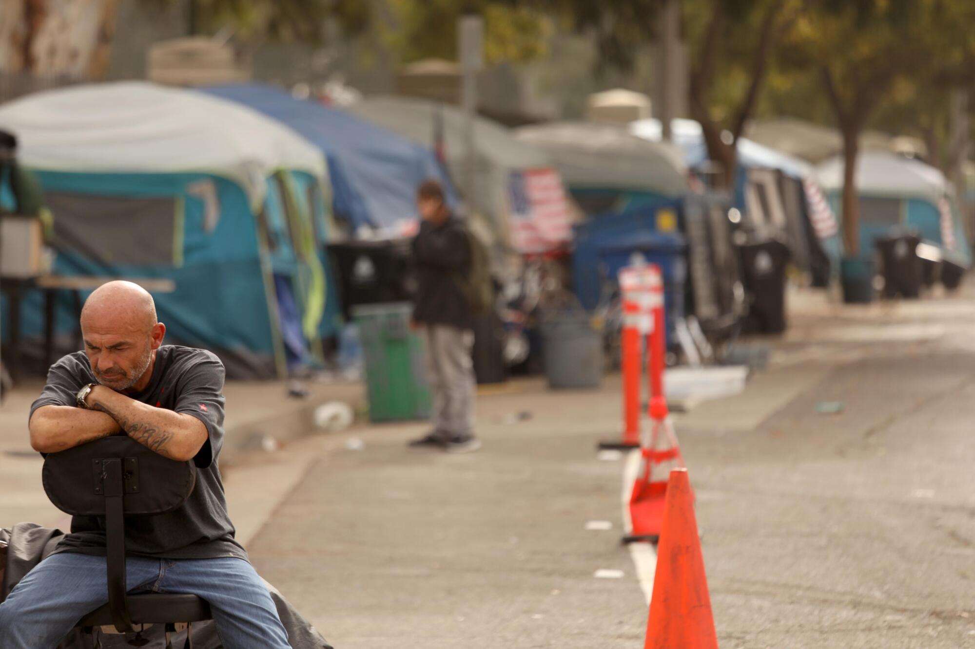 A homeless veteran sits outside his tent.