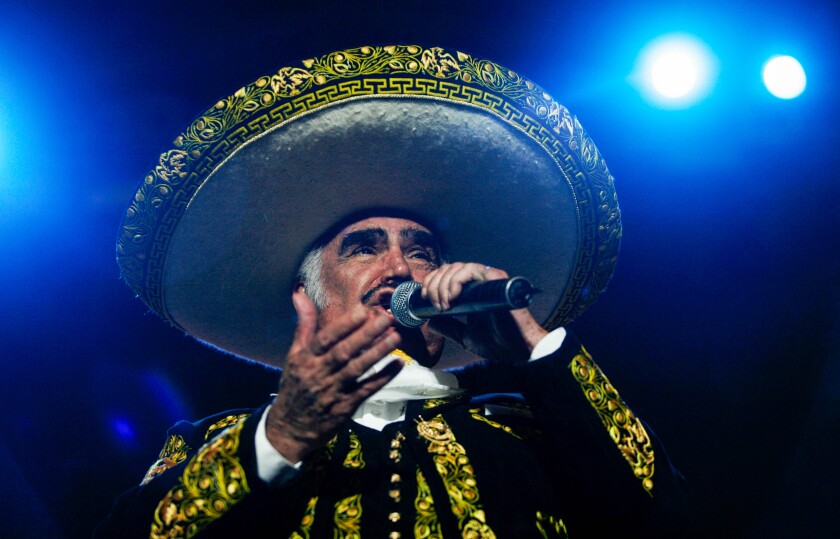 A man in mariachi attire sings in concert