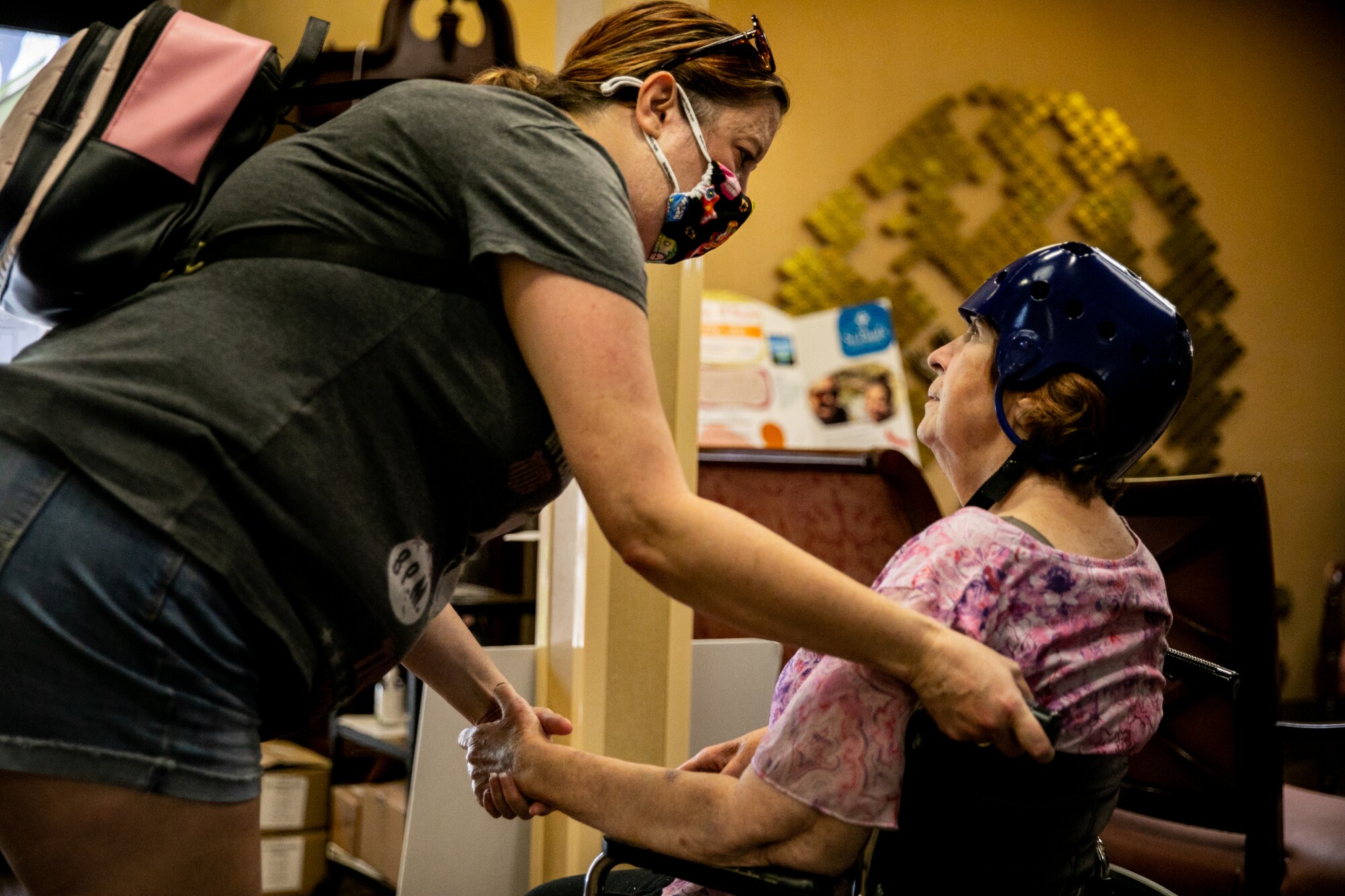 Jen Potter grasps her mother Rita Bumbera's hand as they meet at St. Paul's Senior Services Nursing and Rehabilitation center