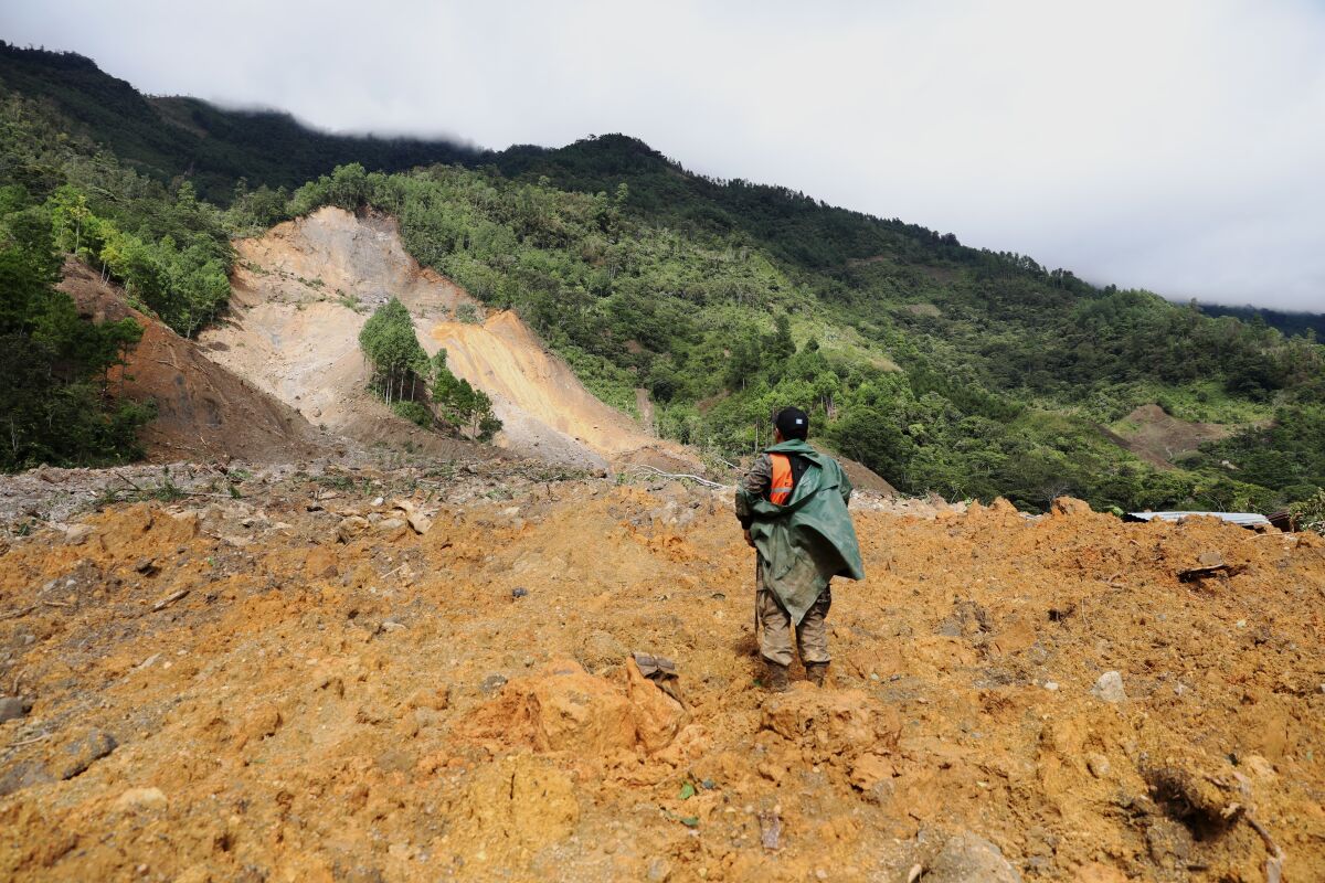 A member of a search and rescue team looks for survivors through the destruction caused by a massive, rain-fueled landslide in the village of Queja, in Guatemala, Saturday, Nov. 7, 2020, in the aftermath of Tropical Storm Eta. (Esteban Biba/Pool Photo via AP)
