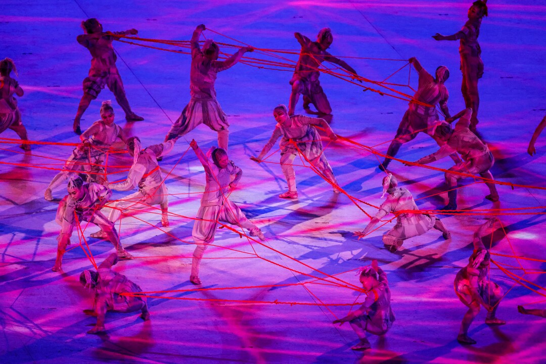 Dancers carry red streamers onstage