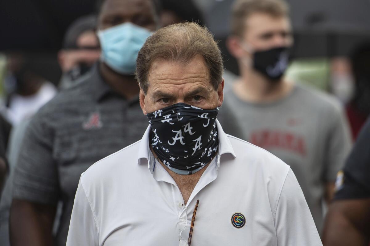 Alabama coach Nick Saban walks onto the field wearing a mask.
