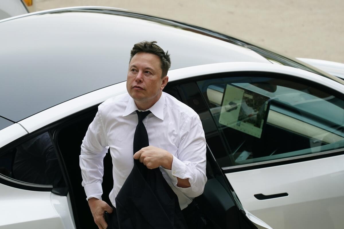 Elon Musk gets out of a car at the justice center in Wilmington, Del.