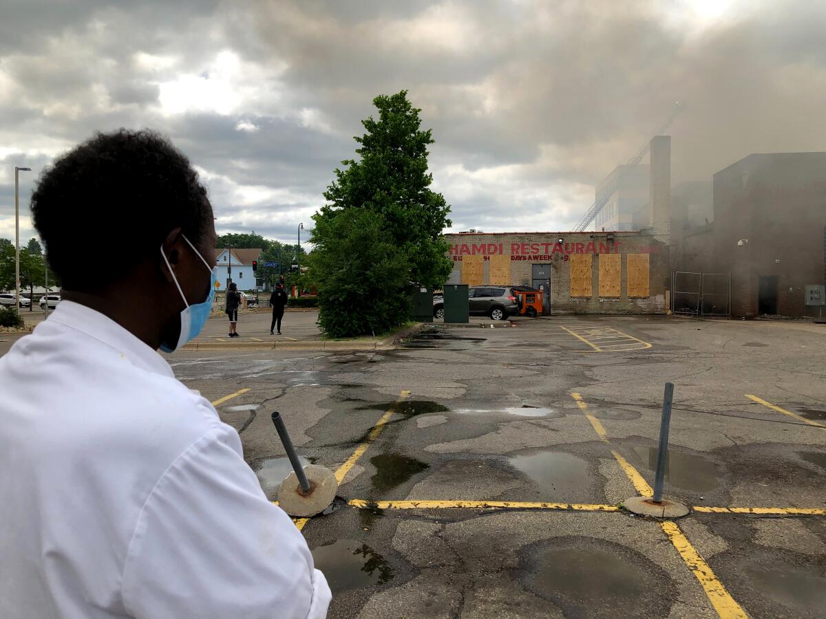 Abdishakur Elmi watches firefighters try to extinguish a blaze next to his Somali restaurant Friday.