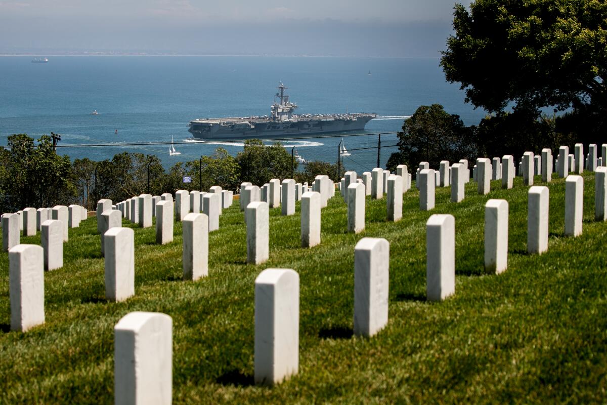 The aircraft carrier USS Theodore Roosevelt leaves San Diego as seen from Fort Rosecrans National Cemetery.
